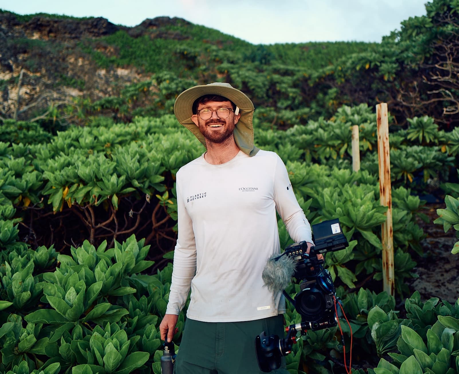 Ricky Rhodes on Henderson Island, holding a camera, emerging from dense jungle